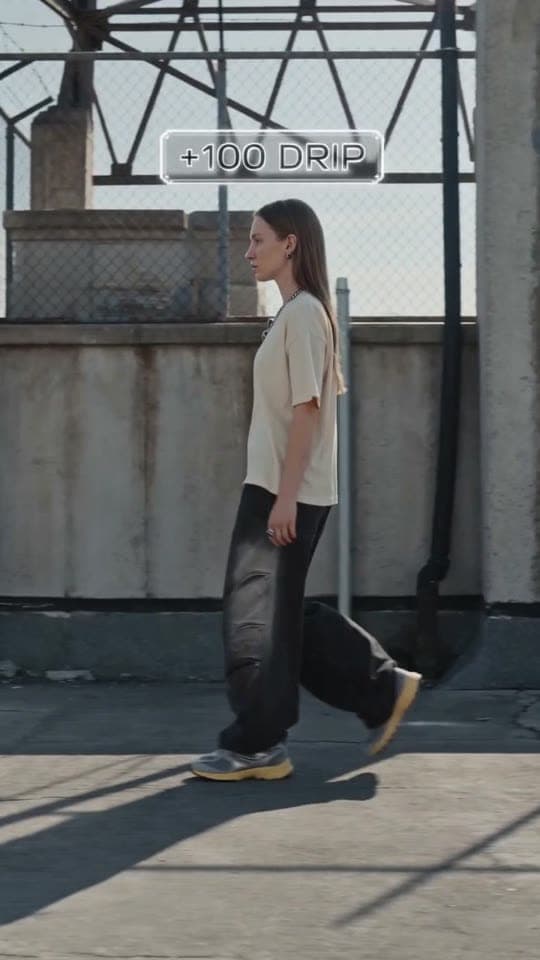 oxkyy strides a rooftop; a gamified HUD scans the sneaker and stacks a '+100 DRIP' counter.